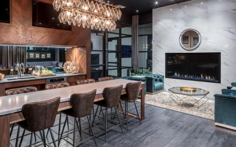 luxurious clubhouse kitchen with chandelier over dining table adjacent to fireplace